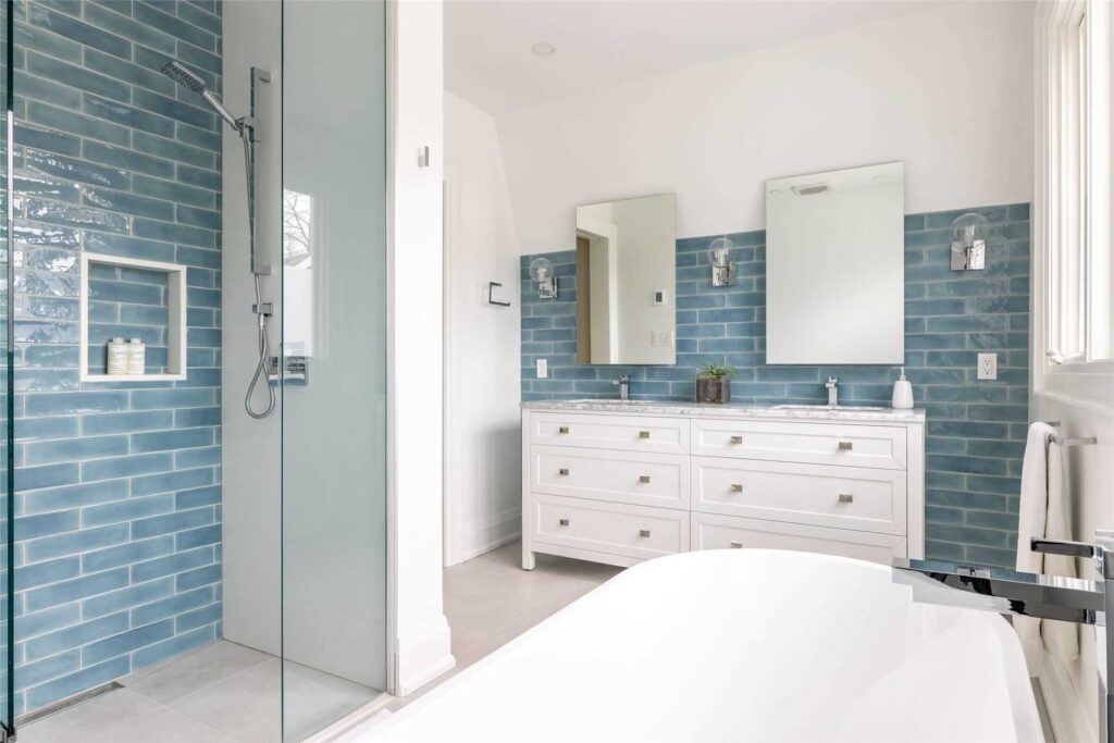 freestanding tub, bathtub, prefab vanity, double vanity, bathroom reno, ensuite, primary bedroom, wall sconce, niche, blue tile, curbless shower